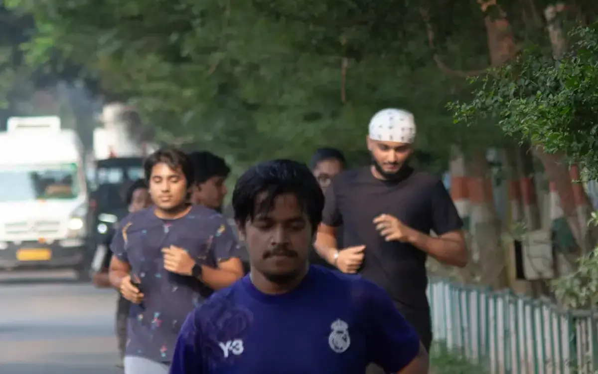 A Verve runner in a blue jersey mid-stride on a tree-lined road with other runners behind